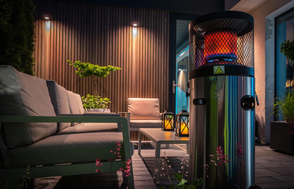 A cozy outdoor patio at night featuring modern outdoor furniture, warm lighting, and an electric patio heater, ideal for relaxing in your home and garden.