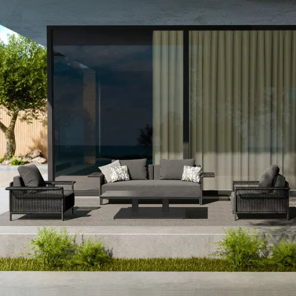 Elegant outdoor sectional sofa with plush gray cushions and decorative pillows, accompanied by a modern coffee table, set on a stylish rug in a serene patio environment, perfect for upscale outdoor living