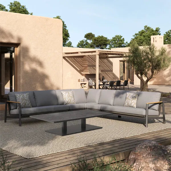 Charcoal grey modular outdoor lounge set with powder-coated aluminium frame and low-profile coffee table, styled on a wooden deck with modern decor.